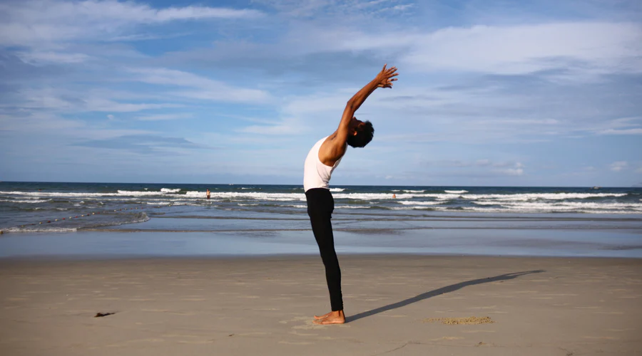 person stretching in the beach to be on top of their health and wellness