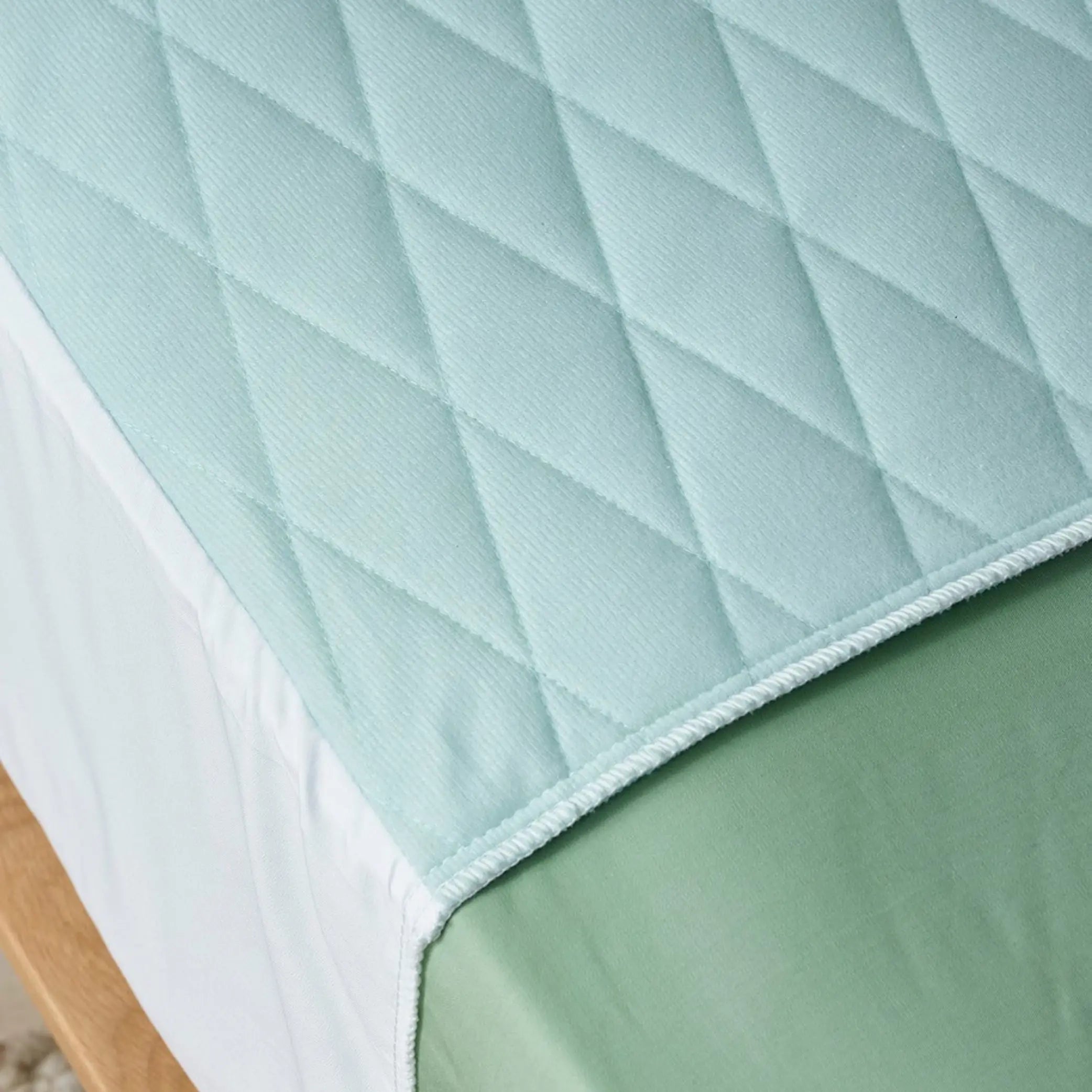 Close-up view of a quilted blue waterproof bed pad, also know as 