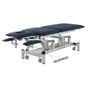 Five-section ComfyCare electric treatment couch in navy blue and white, featuring adjustable sections for postural drainage, an integrated face hole, lower armrest supports, and hands-free foot pedal controls.