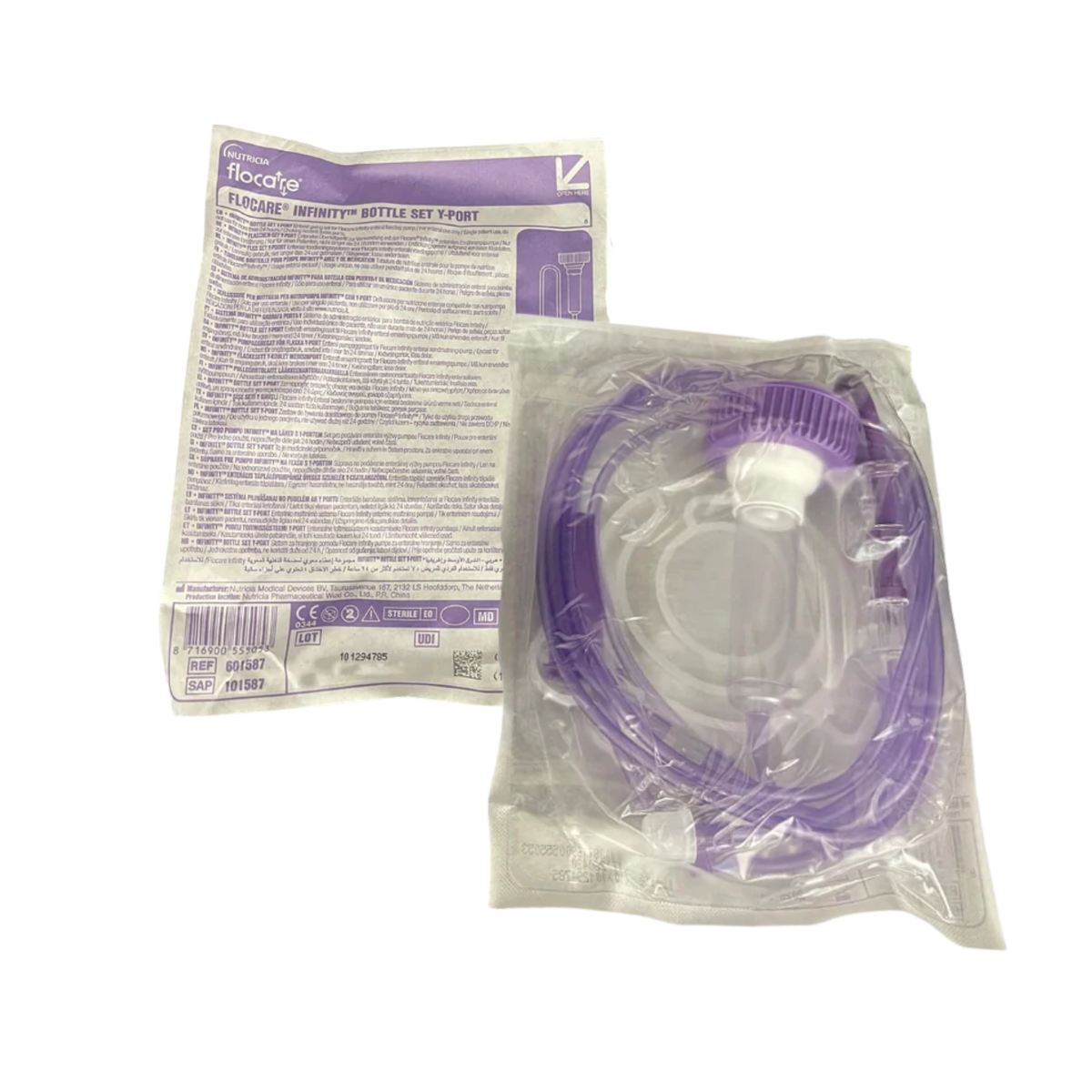 Product packaging view of the Flocare Infinity Bottle Set - Y Port & Drip Chamber inside its sealed clear plastic pouch, displaying the purple product instruction label with barcodes and regulatory symbols alongside the coiled enteral feeding tubing and pump cassette on a transparent background.