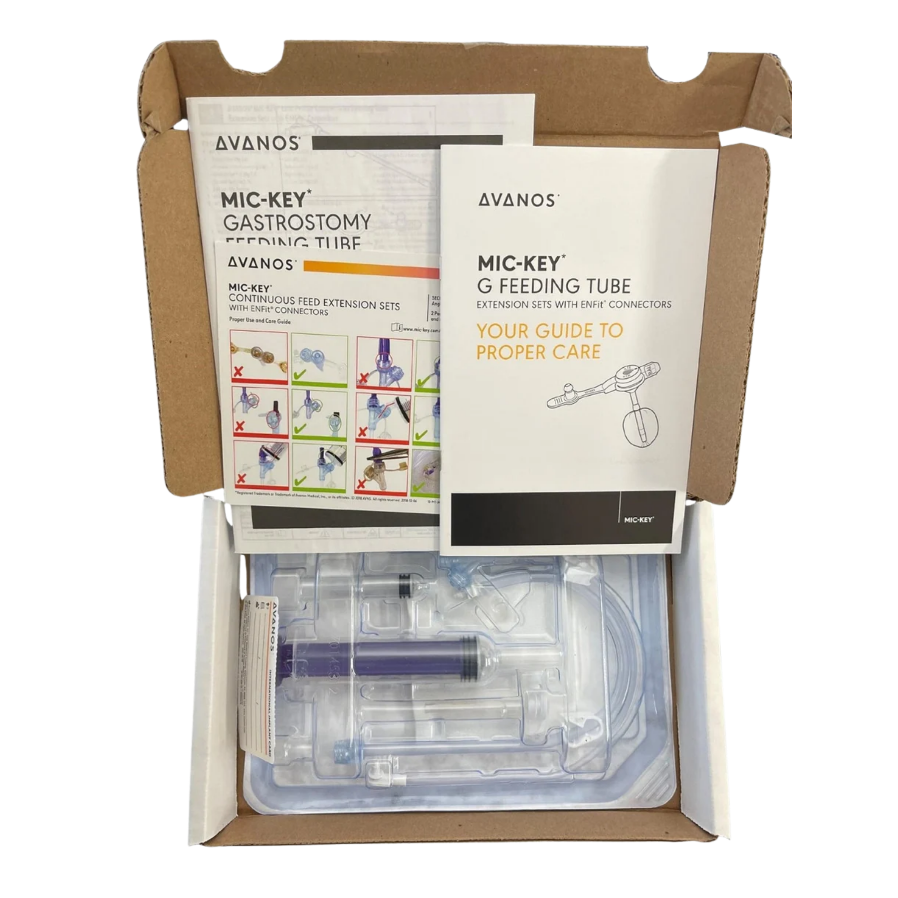 An open top-down view of an unboxed Avanos MIC-KEY Gastric-Jejunal Feeding Tube kit, showing printed instruction booklets on top and a sealed blister package containing enteral feeding components below.