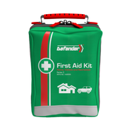 A close-up of the green, zippered softpack carrying case for the Defender Series 3 First Aid Kit. The bag features a red handle, a white first aid cross, a white and red vertical stripe, and is labeled for Home, Vehicle, and Recreation with corresponding icons.