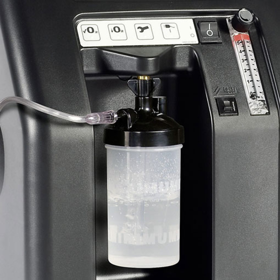 Detailed view of Drive DeVilbiss Oxygen Concentrator with humidifier bottle connected for added moisture during oxygen delivery.
